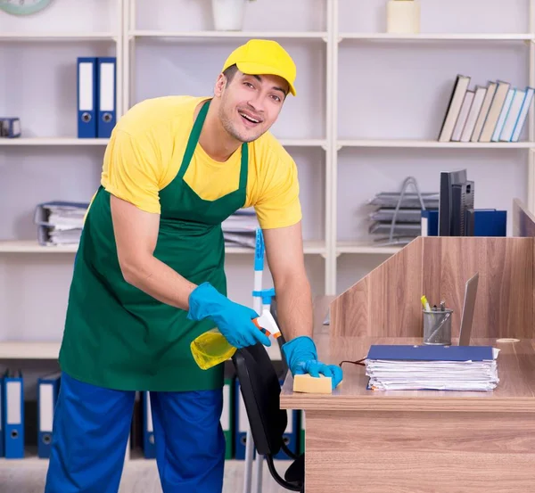 若い男の請負業者がオフィスを掃除する — ストック写真