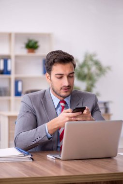 Genç işadamı işyerinde oturuyor.