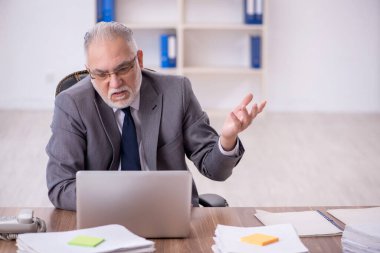 Old businessman employee unhappy with excessive work at workplace