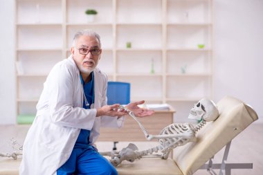 Old male doctor and skeleton patient at the hospital