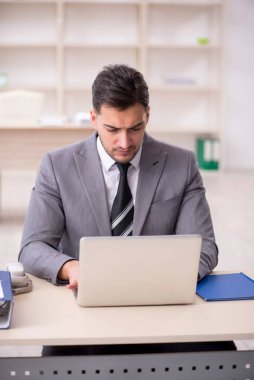 Genç işadamı işyerinde oturuyor.