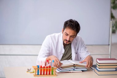 Genç kimyacı öğretmen beyaz tahtanın önünde.