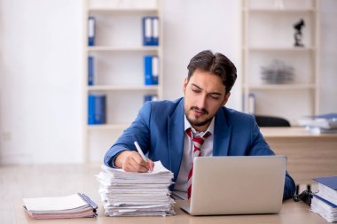 Genç işadamı ve işyerinde çok fazla iş var.