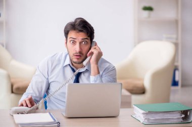 Genç işadamı işyerinde oturuyor.