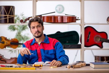 İçeride müzik aletlerini tamir eden genç bir adam.