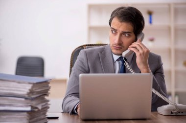 Genç işadamı ve işyerinde çok fazla iş var.