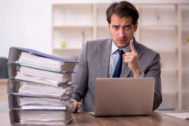 Genç işadamı ve işyerinde çok fazla iş var.