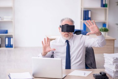 Old businessman employee wearing virtual glasses in the office