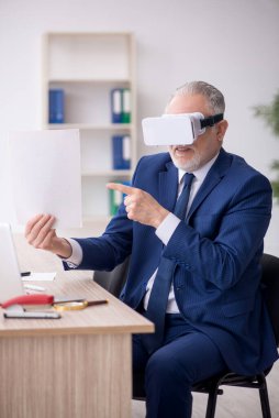 Old businessman employee wearing virtual glasses in the office