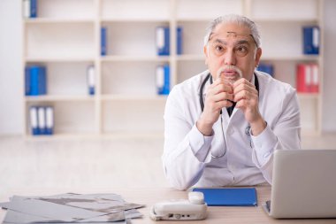 Klinikte çalışan yaşlı erkek doktor.