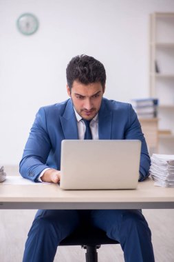 Genç işadamı ve işyerinde çok fazla iş var.