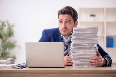 Young employee and too much work at workplace