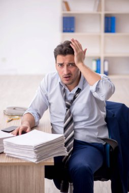 Young employee and too much work at workplace