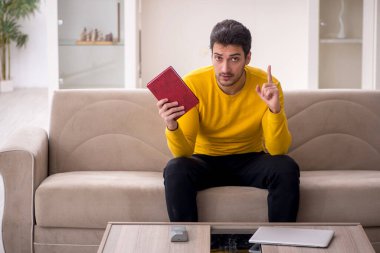 Evde kitap okuyan genç bir öğrenci.