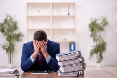 Young employee and too much work at workplace