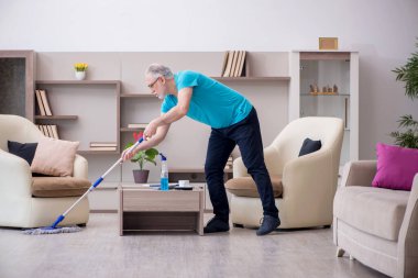 Yaşlı müteahhit evi temizliyor.