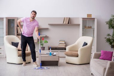 Genç müteahhit evi temizliyor.