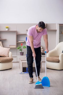 Genç müteahhit evi temizliyor.