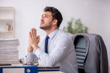 Young employee and too much work at workplace