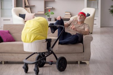 Evde yeni doğan bebeğe bakan yaşlı bir adam.