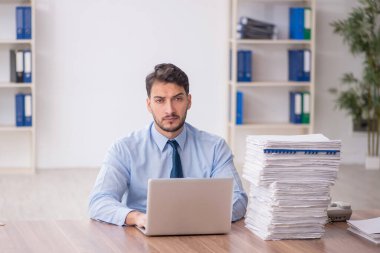 Young employee and too much work at workplace