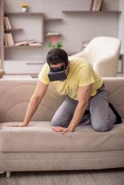 Genç erkek öğrenci evde sanal gözlüklerle eğleniyor.