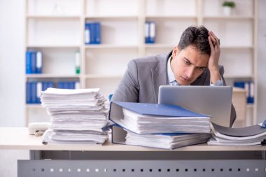 Young employee and too much work at workplace