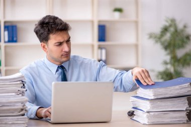 Young employee and too much work at workplace