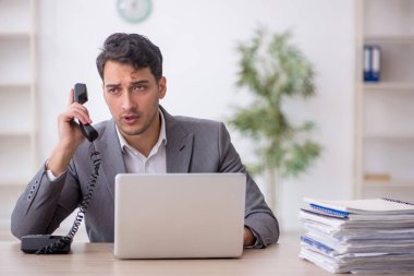 Young employee and too much work at workplace