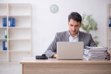 Young employee and too much work at workplace