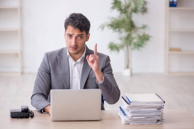 Young employee and too much work at workplace