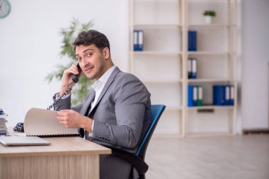 Young employee and too much work at workplace