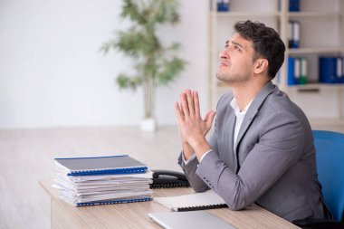 Young employee and too much work at workplace