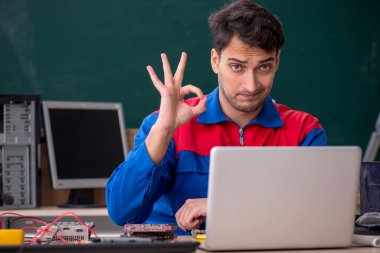 Sınıfta bilgisayar tamir eden genç bir tamirci.