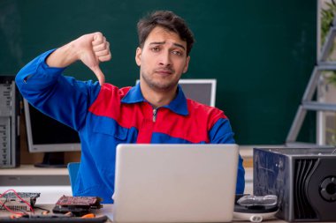 Sınıfta bilgisayar tamir eden genç bir tamirci.