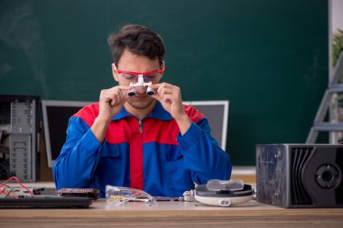 Sınıfta bilgisayar tamir eden genç bir tamirci.