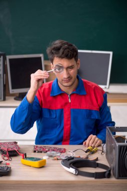 Sınıfta bilgisayar tamir eden genç bir tamirci.