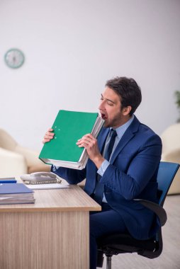 Genç işadamı işyerinde oturuyor.