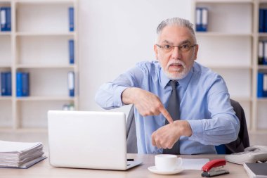 Old employee sitting at workplace