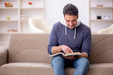 Evde kitap okuyan genç bir öğrenci.