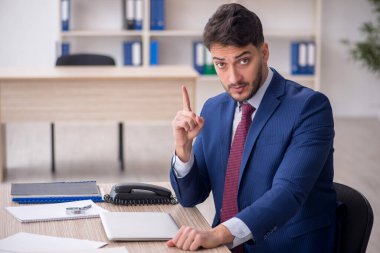 Genç işadamı işyerinde oturuyor.