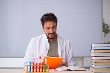 Genç kimyacı öğretmen beyaz tahtanın önünde.