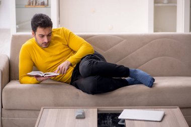 Evde kitap okuyan genç bir öğrenci.