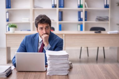 Young employee and too much work at workplace