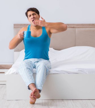 Genç adam yatakta uyanıyor.