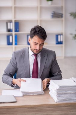 Young employee and too much work at workplace