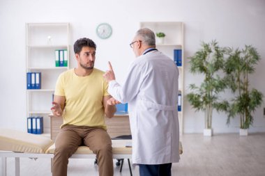 Genç hasta yaşlı doktoru ziyaret ediyor.