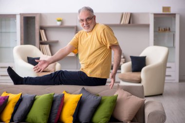 Evde bir sürü yastığı olan yaşlı bir adam.