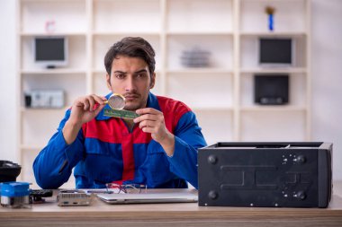 Atölyede bilgisayar tamir eden genç bir tamirci.