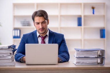Genç işadamı ve işyerinde çok fazla iş var.